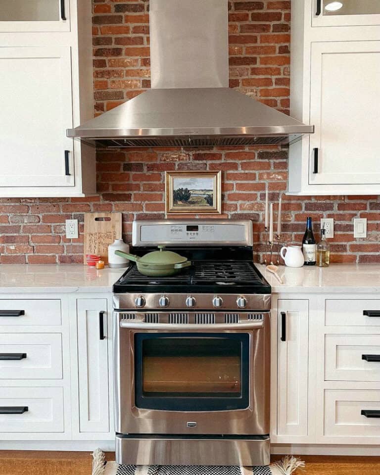 white kitchen cabinets with brick backsplash feature