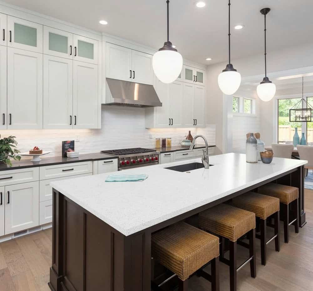 White quartz countertops work in harmony with white cabinets and sleek brown wood flooring