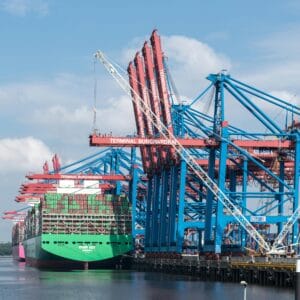 Cranes and container ships at Terminal Burchardkai in Hamburg port on a clear day.