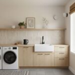 Beige textured tile backsplash behind a white farmhouse sink, with light wood cabinets and minimal decor, in a bright, modern.