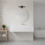 Modern bathroom featuring pearl shell tile wall behind a sleek white sink and round mirror.