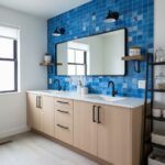 A stylish bathroom featuring a vibrant blue glass tile backsplash behind dual sinks, complemented by a large mirror and conte.