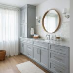 Elegant bathroom with mother of pearl shell tile backsplash and light gray cabinetry. Bright, airy space with a round mirror.