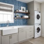 Bright laundry room featuring a blue glass tile backsplash behind the sink and shelves.