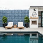Poolside area featuring glass tile backsplash, lounge chairs, and decorative elements.