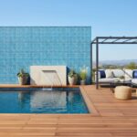 Poolside glass mosaic tile wall with water feature and outdoor seating area.