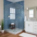 Modern bathroom featuring a glass tile shower with blue mosaic tiles and a white vanity with a mirror.