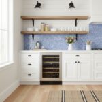 Modern kitchen with blue glass mosaic tile backsplash, white cabinetry, and open wooden shelves.