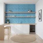 A stylish kitchen featuring a vibrant blue glass mosaic tile backsplash with open wooden shelves and minimalist decor.