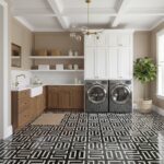 Black and white geometric patterned tile in laundry room with beige walls and white cabinetry.