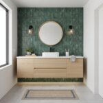 Green peel and stick wall tile behind bathroom vanity with round mirror and black fixtures.