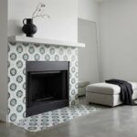 Blue and white patterned ceramic tile around fireplace with black mantel and minimalist decor.