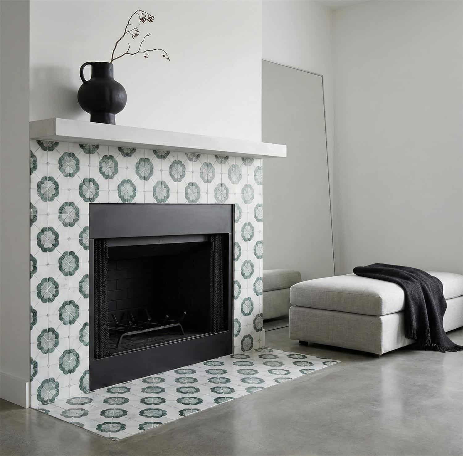 Blue and white patterned ceramic tile around fireplace with black mantel and minimalist decor.