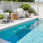 Bright outdoor space featuring a swimming pool with glass tile backsplash and comfortable seating area.