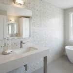 Up of a bathroom wall featuring mother of pearl shell tiles in a mosaic pattern, creating a shimmering, elegant surface.