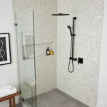 Modern shower with mother of pearl shell tile walls and black fixtures, creating a luxurious and elegant bathroom design.