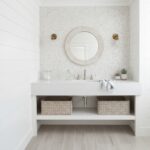 Bathroom vanity with pearl shell tile backsplash and mirror, featuring a white countertop and wicker baskets for storage.