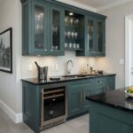 A stylish kitchen featuring blue cabinetry, a shell tile backsplash, and modern appliances, creating a sophisticated and coas.