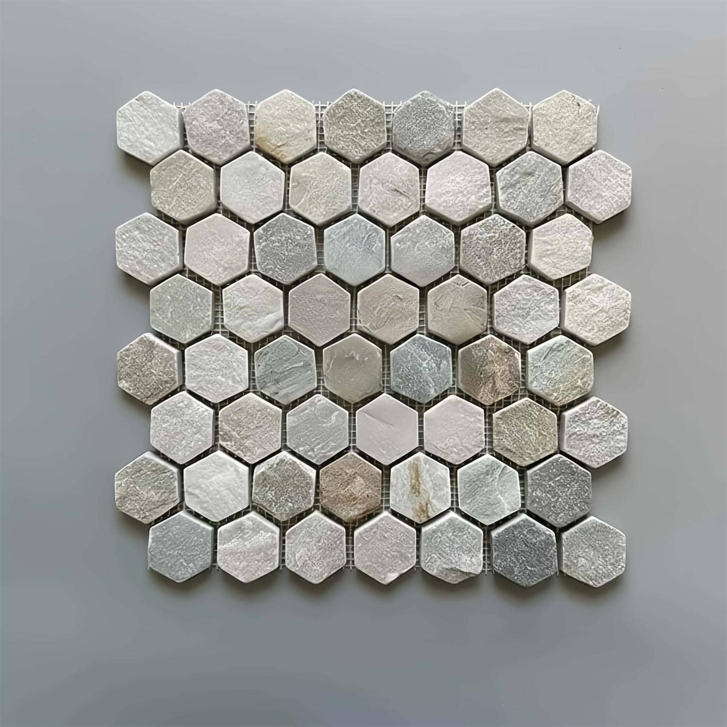 A close-up of marble hexagon tiles featuring a mix of beige, gray, and cream colors with a polished, smooth texture.