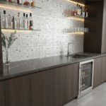 Up of a kitchen backsplash with mother of pearl shell tiles, creating a shimmering, elegant surface behind the sink and count.