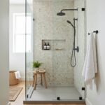 A sleek shower with mother of pearl shell tiles creating a luminous, textured wall. Perfect for adding elegance and natural b.