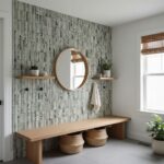 A textured green tile wall with vertical ridges, complemented by a round mirror, wooden shelves, and natural decor in a brigh.