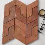Red clay tiles with a textured surface and geometric cutout pattern.