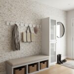 Interior view of a modern entryway with a mother of pearl shell tile accent wall, white storage cabinet, and round mirror.