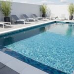 Pool with glass mosaic tile and modern lounge chairs, outdoor setting.