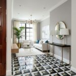 Bright living room with black, white, and gold geometric patterned tile flooring. Features a white sofa, gold accents, and la.