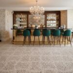 Teal upholstered bar stools with mosaic patterned tile floor in a luxurious bar setting.