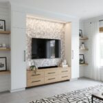 Modern living room with peel and stick wall tile behind flat-screen TV, featuring a light wood cabinet and decorative accents.