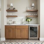 Small kitchen area featuring a shell tile backsplash, wooden cabinets, and open shelves with glassware and decorative items.