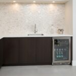 Modern kitchen with a mother of pearl shell tile backsplash and dark cabinetry.