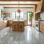Bright kitchen featuring natural wood cabinets and a patterned black and white tile floor. Large window and potted plants add.