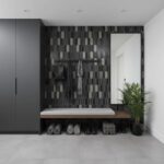 Modern entryway with black peel and stick wall tiles, mirror, and bench.