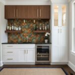 Up of peel and stick tile backsplash in a modern kitchen with white cabinets and a wine cooler.