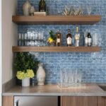 Blue glass mosaic tile backsplash behind a bar area with bottles and glassware.