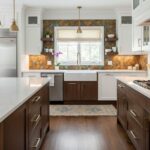 A stylish kitchen featuring peel and stick tile backsplash with warm tones, white cabinetry, and a farmhouse sink for a conte.