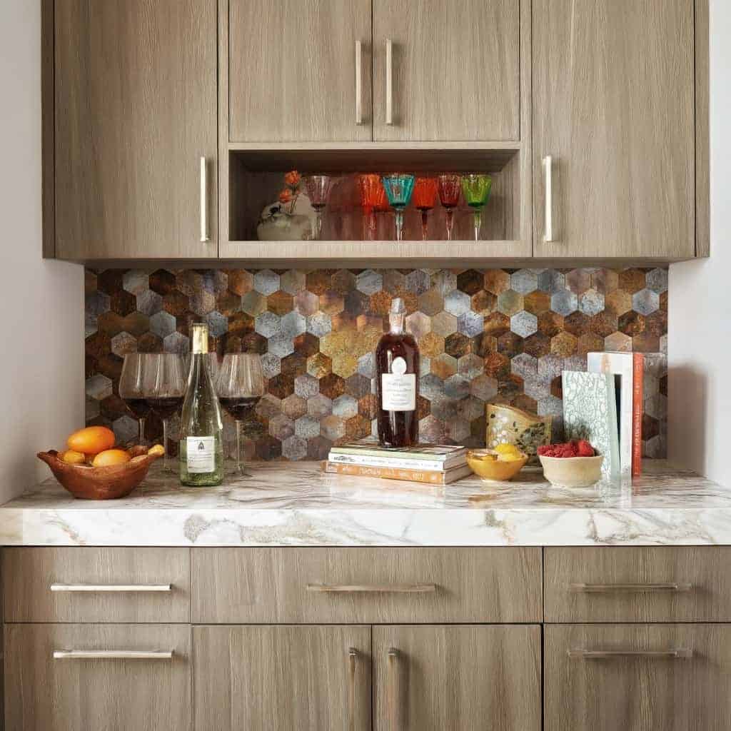A modern kitchen with a colorful peel and stick tile backsplash, featuring hexagonal tiles in various earthy tones above a ma.