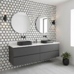 Two round mirrors above black vessel sinks with peel and stick tile backsplash.