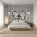 A bedroom featuring a gray vertical striped tile wall behind the bed, with round mirrors, wall sconces, and minimalist decor.