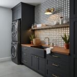 Bright laundry room with dark blue cabinets, wooden countertop, and hexagonal patterned wall tiles in black and white.