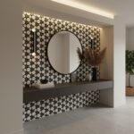 Black and white geometric patterned tile wall with a round mirror and decorative vases.