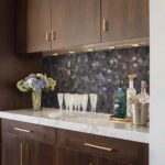 A modern kitchen featuring a peel and stick tile backsplash with a dark, textured pattern behind a white marble countertop.