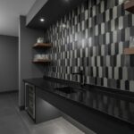 Peel and stick tile backsplash in a modern kitchen with dark hexagonal tiles and wooden shelves. Easy DIY wall upgrade for co.