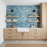 Glass tile backsplash with blue mosaic tiles behind kitchen sink.