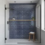 Blue glass tile backsplash in a contemporary shower with mosaic details and a wooden stool for accessories.