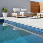 Poolside area featuring glass tile backsplash and outdoor lounge furniture.