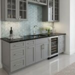 Bright gray kitchen with peel and stick wall tiles behind the sink and countertop. Modern cabinetry and a wine cooler complet.